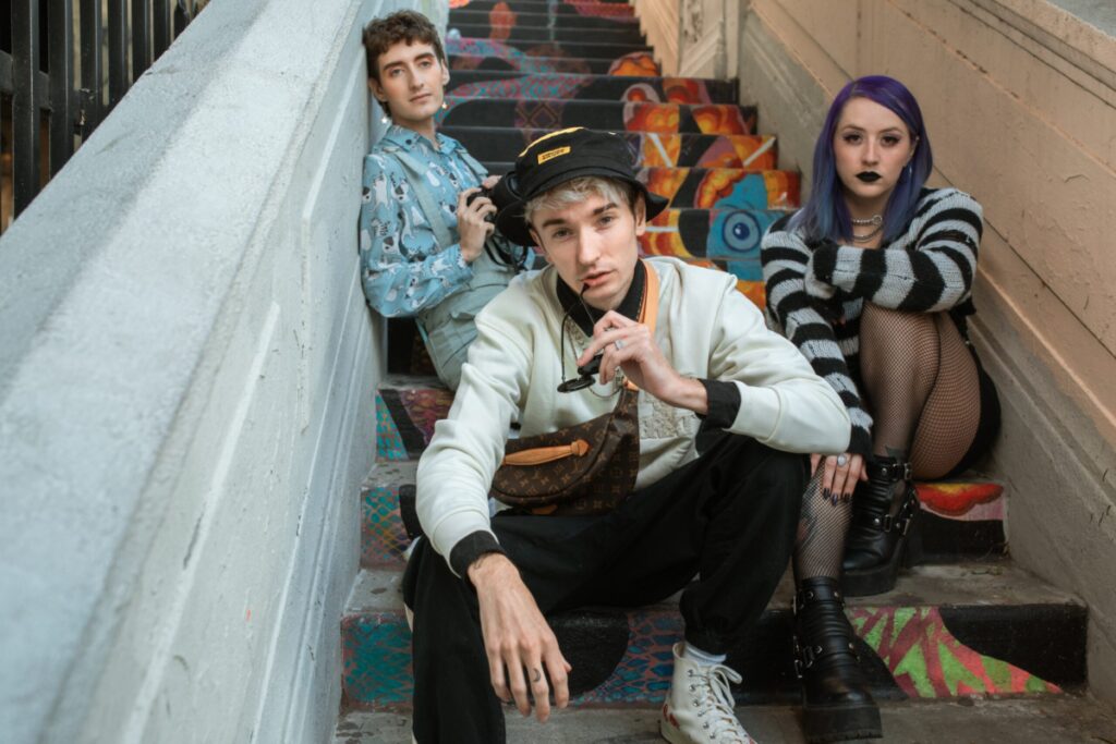 Three young pansexual people sit in a stairwell